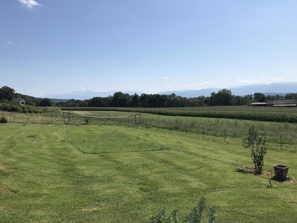 A rural landscape with a grassy field, a small structure, and distant mountains.