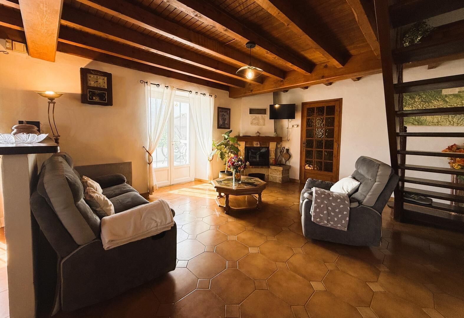 A living room with a sofa, armchair, and a fireplace.