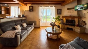 Een gezellige woonkamer met een bank, een bijzettafeltje, een open haard en een televisie.