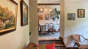A cozy living room with a sofa, a wicker chair, and a dining area with a table and chairs.