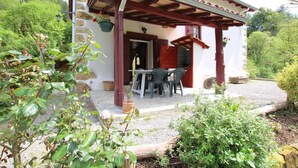 A rustic building with a stone facade, a wooden pergola, and a gravel patio with outdoor seating. - PUTTIKO - BANCA - Gîte (BANCA)