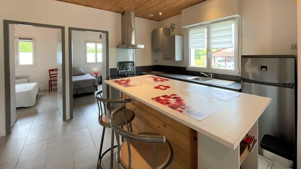 A modern kitchen with a central island, stainless steel appliances, and a wooden ceiling. - Chez Claverie - Hasparren (HASPARREN)
