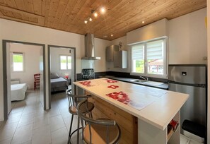 A modern kitchen with a central island, stainless steel appliances, and a wooden ceiling. - Chez Claverie - Hasparren (HASPARREN)