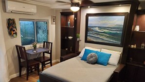 Une chambre à coucher avec un lit, un bureau et une chaise. Il y a une fenêtre donnant sur l’océan.