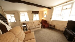 A cozy living room with a sofa, a red armchair, a television, and a fireplace. - Holiday Cottage In The Village Of Dent In The Yorkshire Dales - Dog friendly (Dent)