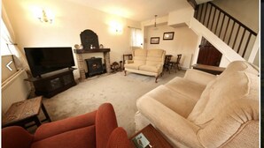 A living room with a fireplace, a television, and a staircase. - Holiday Cottage In The Village Of Dent In The Yorkshire Dales - Dog friendly (Dent)
