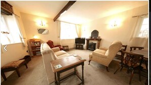 A cozy living room with a sofa, armchairs, a wooden coffee table, a fireplace, and a television. - Holiday Cottage In The Village Of Dent In The Yorkshire Dales - Dog friendly (Dent)