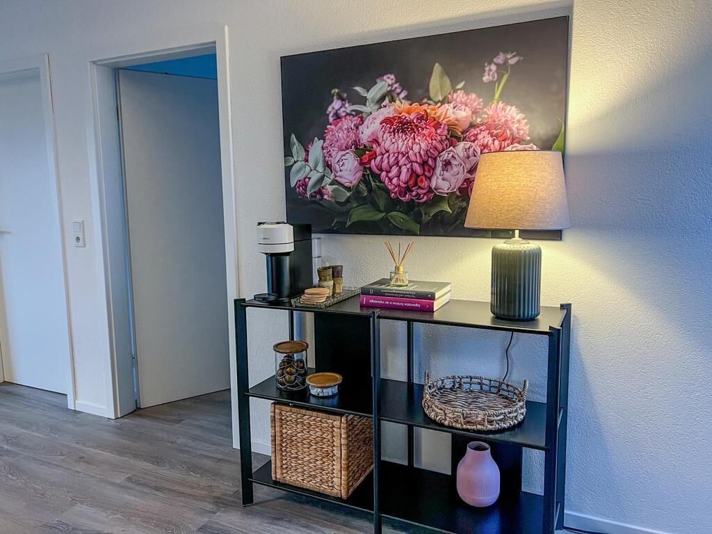 A hallway with a black console table displaying books, a lamp, and decorative items.
