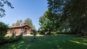 A rustic wooden cabin with a sloped roof, surrounded by a well-maintained lawn and large trees. - Gite de Pernaout - BELIS (BELIS)