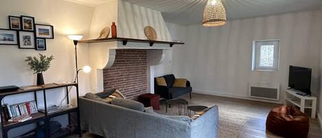 A modern living room with a sofa, a coffee table, a fireplace, a bookshelf, and a television.