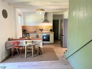 Cocina compacta con comedor, que incluye una mesa de madera, sillas, cafetera y refrigerador.