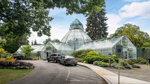 A greenhouse with a dome structure, a parking area with marked spaces, and a pathway leading to the entrance. - Bright & Spacious 2 BR Near Waterfront (Tacoma)