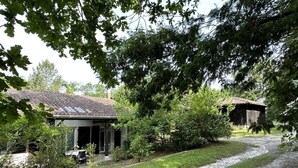 Ein rustikales Haus mit Kiesweg, umgeben von üppiger Vegetation und Bäumen.