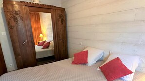 Ein Schlafzimmer mit einem Bett, einem Holzschrank mit Spiegel und einem weißen Kopfteil.