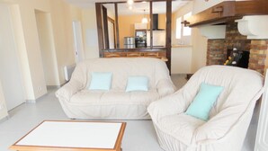 A living room with a beige sofa, a matching armchair, and a wooden coffee table. - Chez Régine - Angoume (ANGOUME)