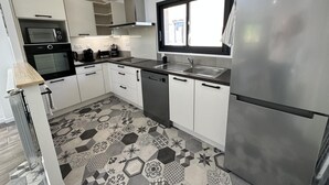 A modern kitchen with white cabinets, stainless steel appliances, and a patterned tile floor.