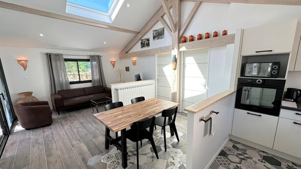 A modern kitchen with a wooden table and chairs, a built-in oven, and a skylight.