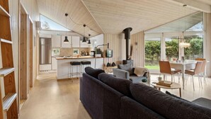 A spacious living area with a dark sofa, a dining table with chairs, and a kitchen area with modern appliances and pendant lighting. - Lovely home in Vejby with kitchen (Vejby)