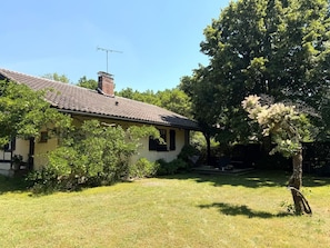 Une maison avec un toit en tuiles, une cheminée et un arbre dans la cour.