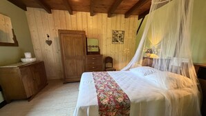 Een slaapkamer met een bed, een houten kledingkast en een klein tafeltje met een lamp.