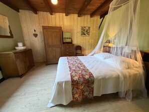 A bedroom with a bed, wooden wardrobe, and a small table with a lamp.