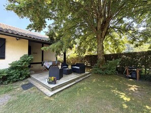 A patio with outdoor furniture, a tree, and a building with a tiled roof.