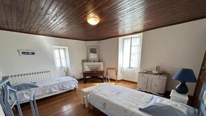A bedroom with two beds, a dresser, a chair, and a desk.