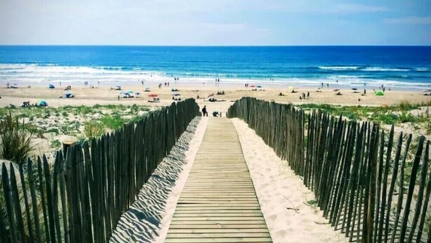 A wooden boardwalk leading to a beach with people and umbrellas. - Jouanon - Bias - Gîte (BIAS)