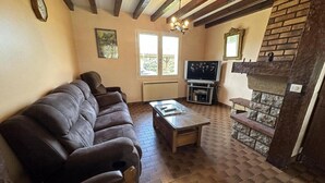 A living room with a sofa, a coffee table, a fireplace, and a television. - Jouanon - Bias - Gîte (BIAS)