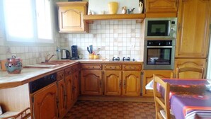 A kitchen with wooden cabinets, a tiled backsplash, a stove, and a dishwasher. - Jouanon - Bias - Gîte (BIAS)