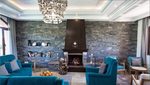 Una sala de estar moderna con chimenea de piedra, sofás color turquesa y un candelabro.