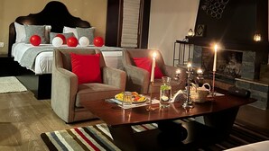 Un dormitorio moderno con cama, sofá, una mesita de centro con velas y chimenea.