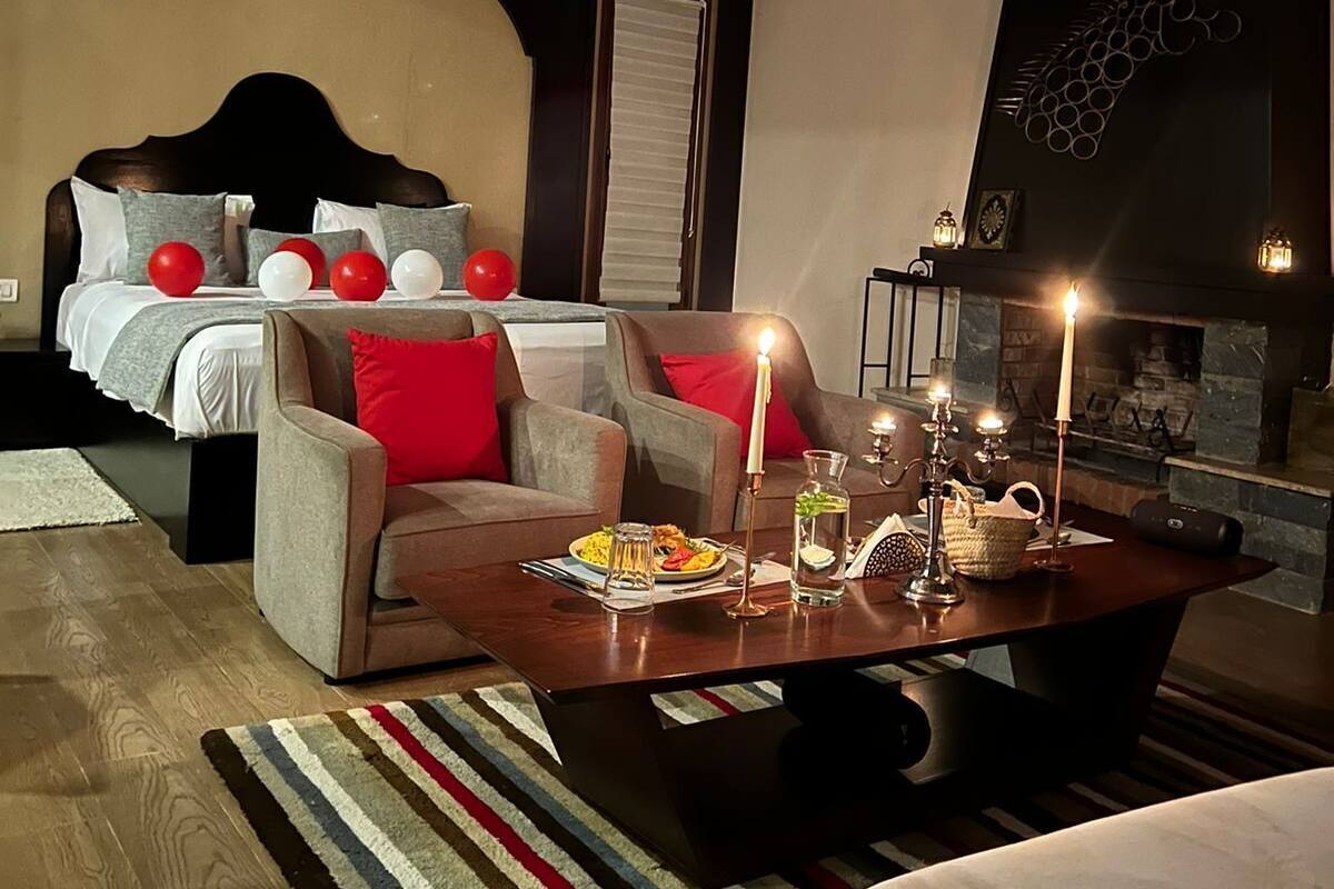 Un dormitorio moderno con cama, sofá, una mesita de centro con velas y chimenea.