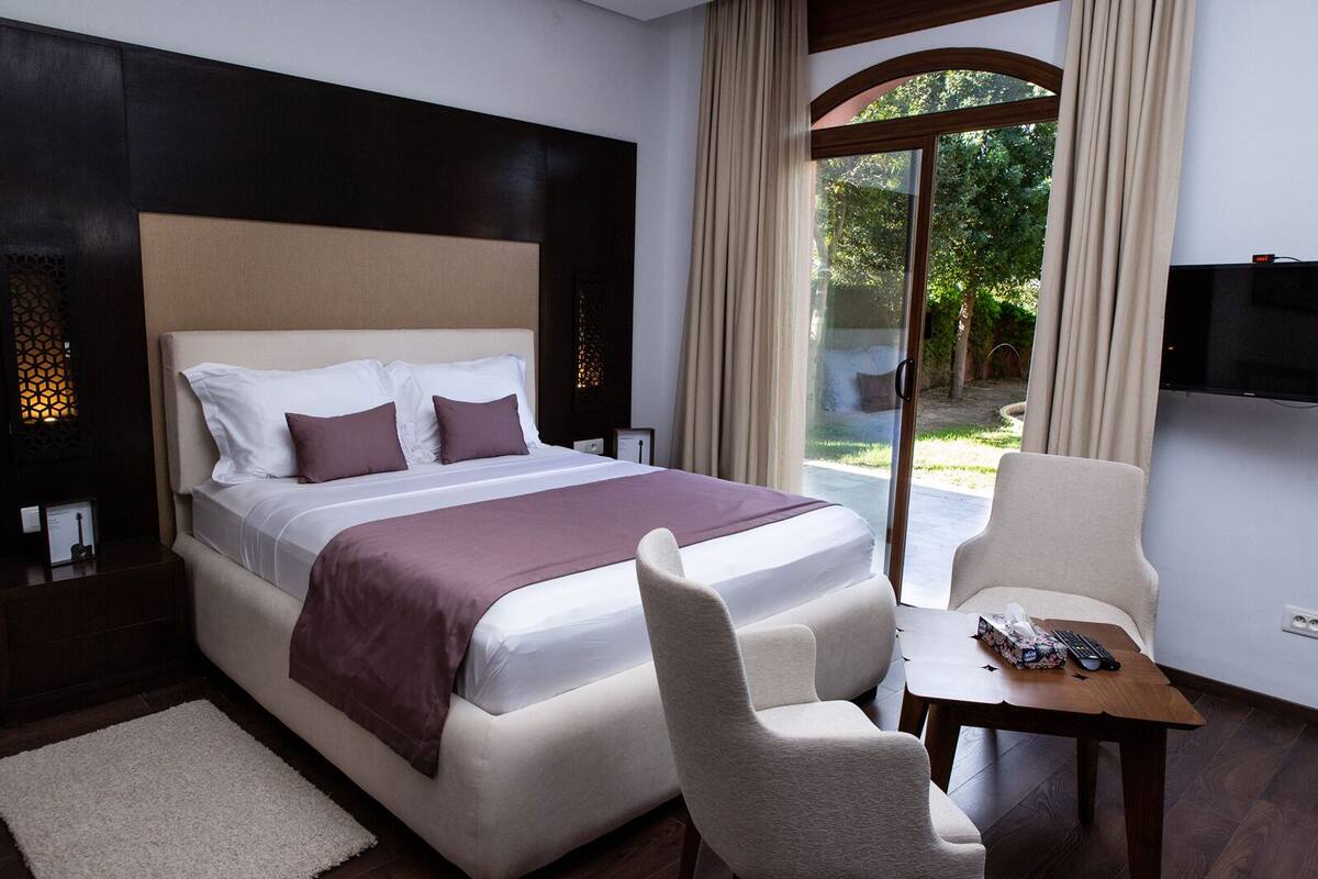 Una habitación de hotel con una cama grande, un escritorio, una silla y un televisor.