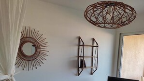 Een woonkamer met een televisie, rieten meubels en decoratieve muurkunst.