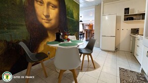 A dining area with a large mural, a chandelier, and modern furniture.
