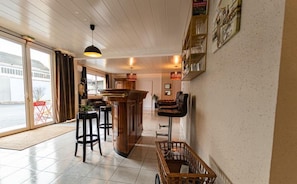 A bar area with stools, a wooden bar counter, and a wicker basket.