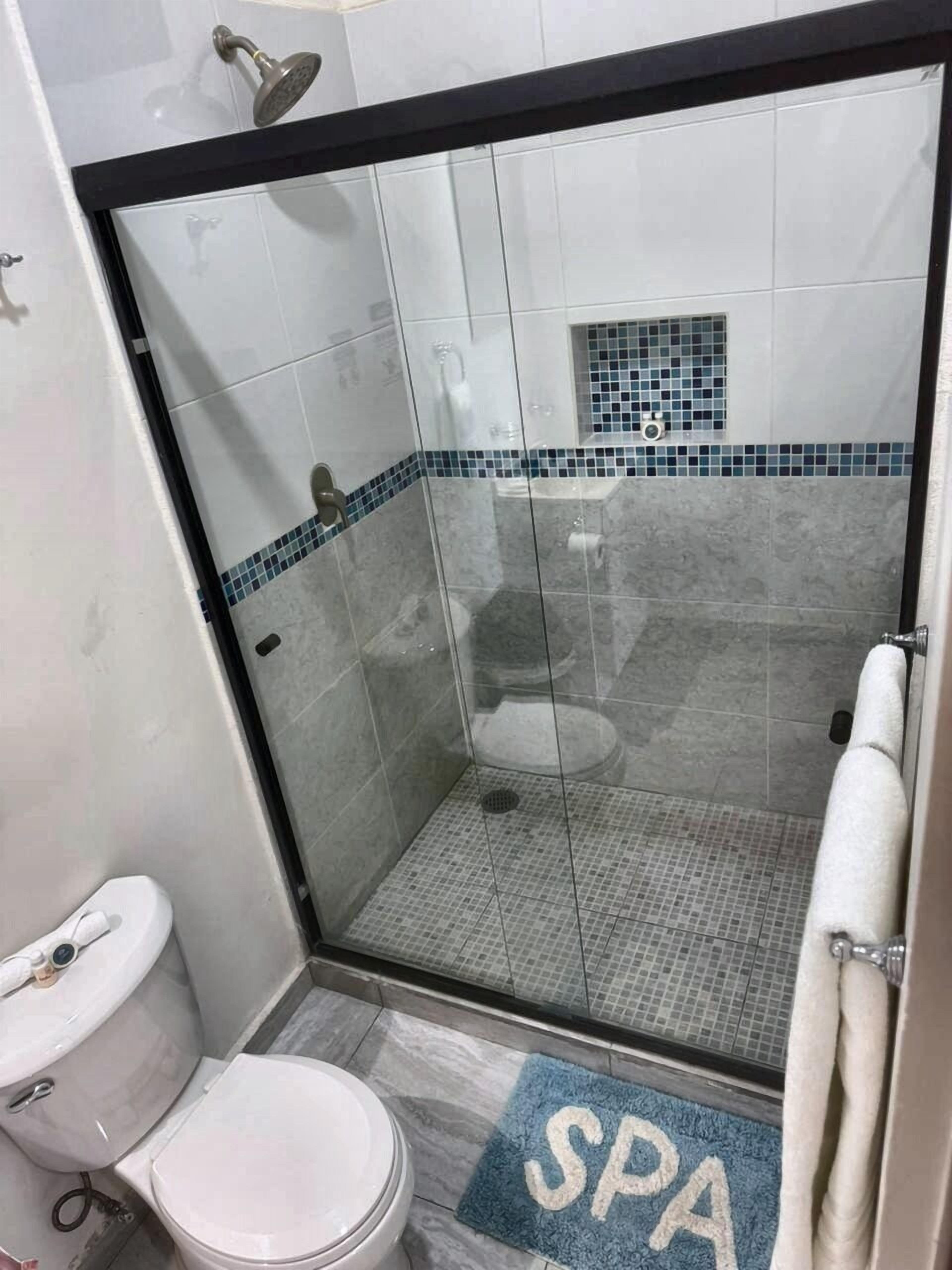 Casa de banho com cabine de duche em vidro, sanita e lavatório.