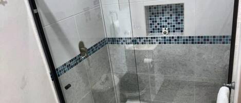 Een badkamer met een glazen douchecabine, toilet en wastafel.