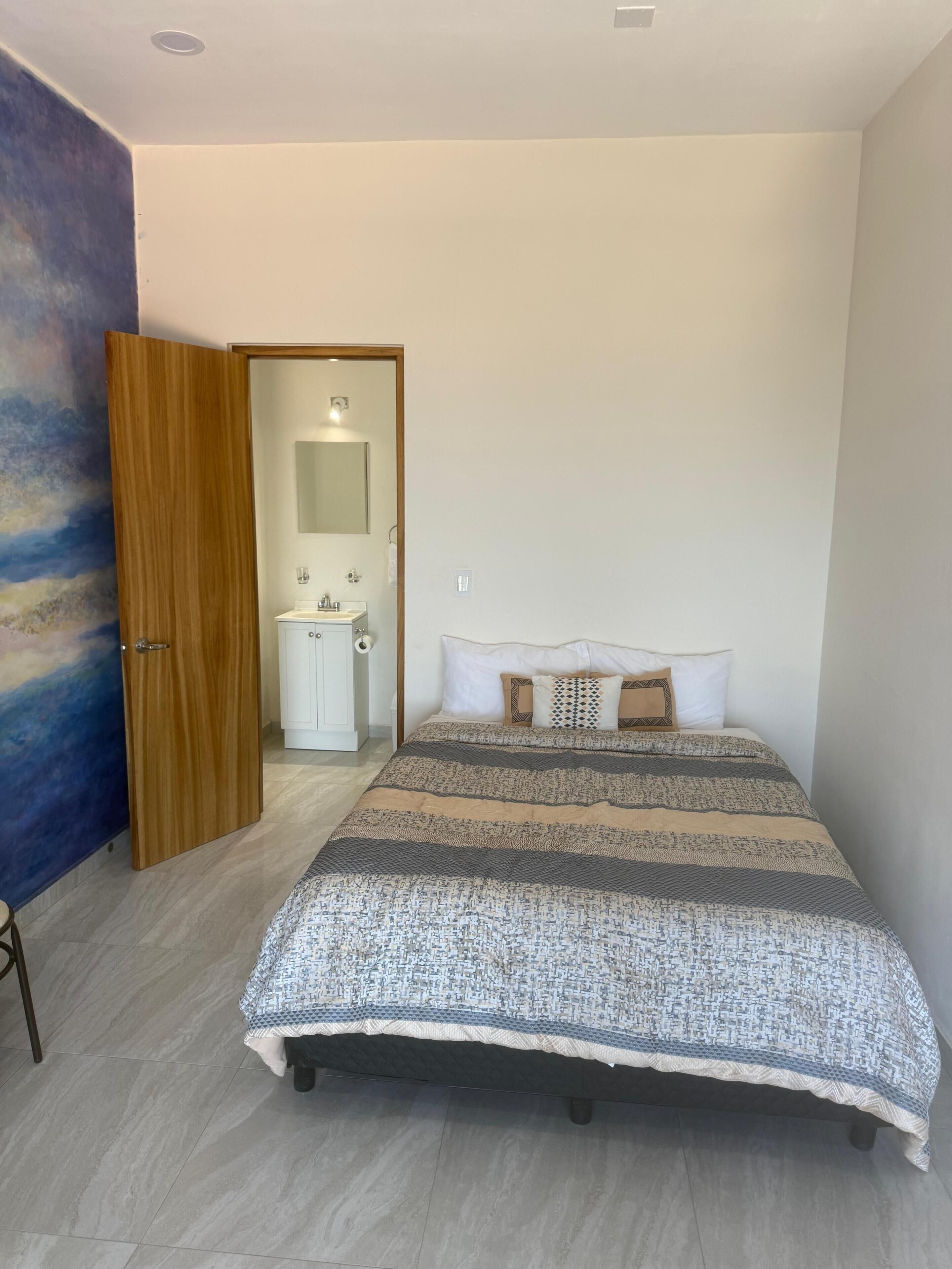 Une chambre à coucher avec un lit, une armoire, une salle de bain et un tableau accroché au mur.