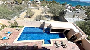 Ein Pool auf dem Dach mit geometrischem Design, umgeben von Liegestühlen und Blick auf das Meer.