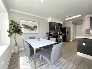 A modern kitchen with dark cabinetry, stainless steel appliances, and a white countertop.