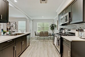 A modern kitchen with dark cabinets, a large island, and a dining area with a table and chairs.