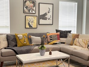 A living room with a sectional sofa, a coffee table, and wall art.