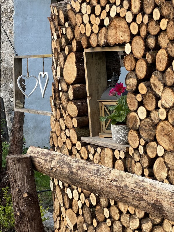 A rustic cabin with a log exterior, a small window with a flower, and heart-shaped decorations.