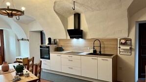 A modern kitchen with white cabinetry, a black range hood, and a wooden countertop. - Wunderschöne, Moderne Ferienwohnung in Österreich mit dem Charme von 1750 (Feistritz im Rosental)