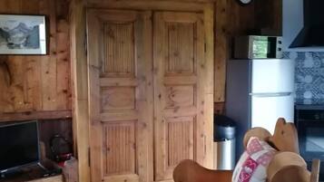 L’intérieur d’un chalet en bois accueillant, avec un canapé, un téléviseur et un coin cuisine équipé d’un four à micro-ondes.