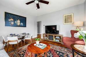 Ein modernes Wohnzimmer mit Essbereich, Deckenventilator, Flachbildfernseher und einem roten Sofa.