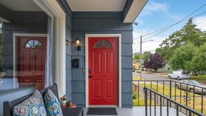 A house with a red door, a porch with a bench, and a street view. - Spacious Stadium District 2BR King Bed (Tacoma)
