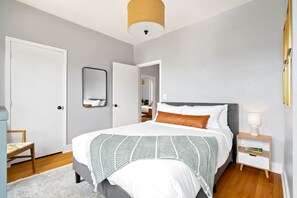 Une chambre à coucher avec un lit, une table de chevet, une chaise et une porte.